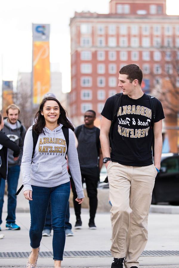 Two students walk in front of another group of students in downtown Lincoln.