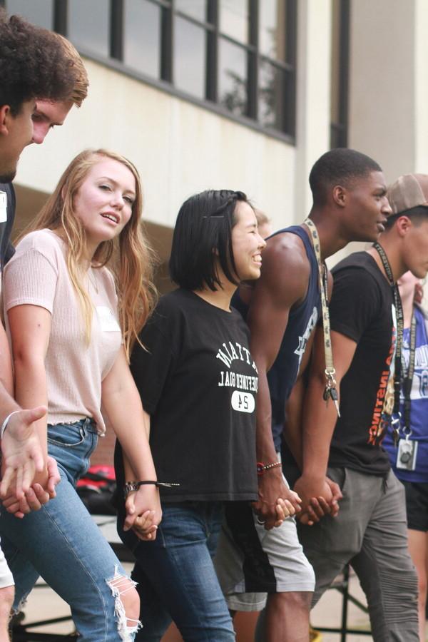 A group of students holding hands and smiling broadly.